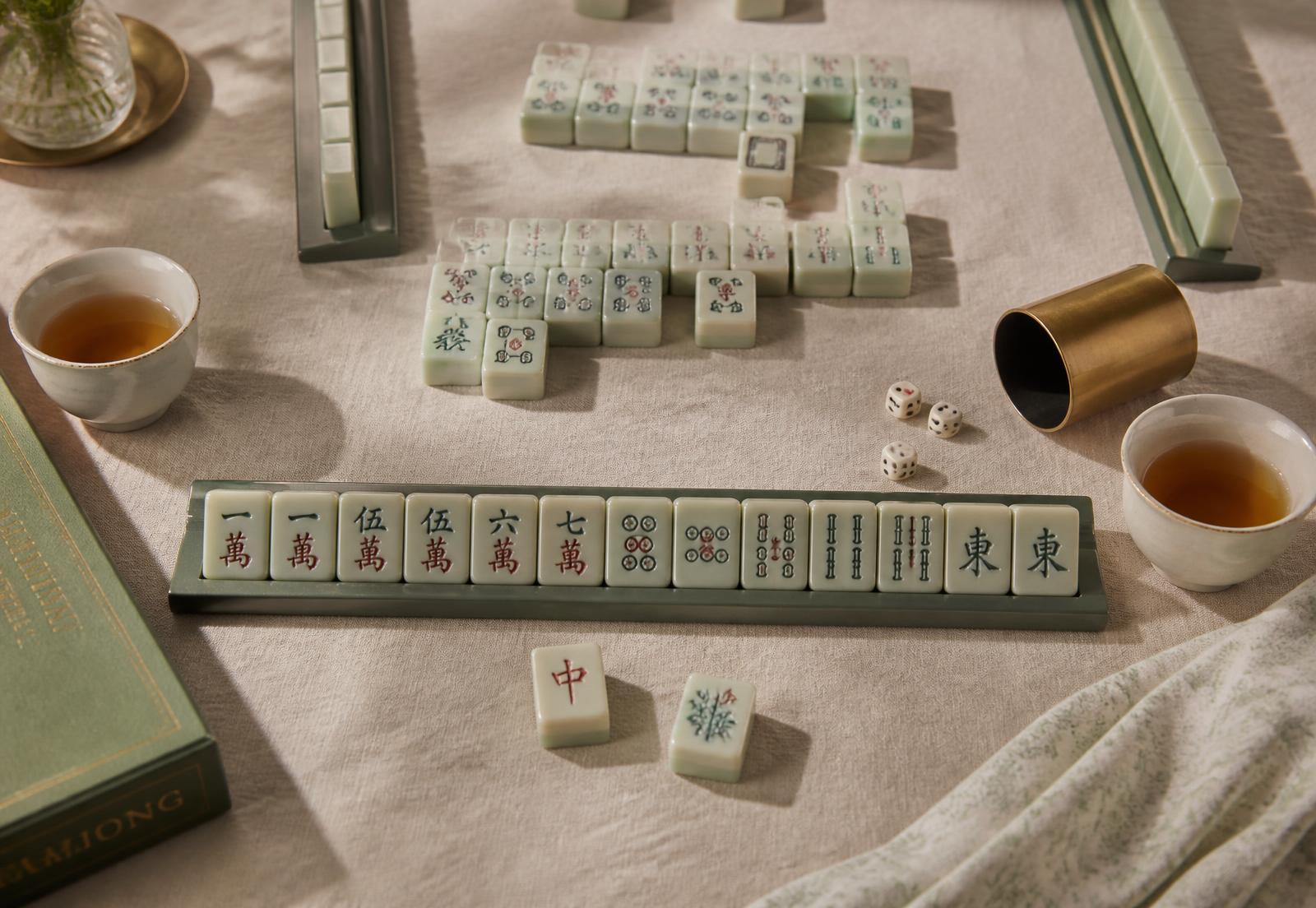 Sea-glass green mahjong tiles set out on a linen tablecloth with tea